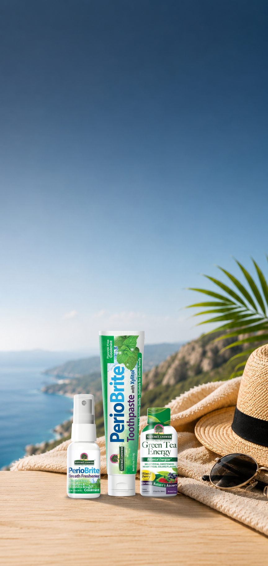 PerioBrite oral care products are displayed on a wooden table with a beach and ocean background, alongside a straw hat, sunglasses, and a towel. Includes toothpaste, breath freshener, and green tea energy shot